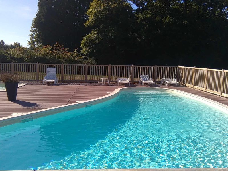 Hébergement touristique avec piscine extérieure entourée de chaises longues confortables.