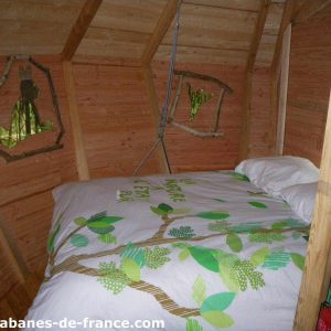 Cabane en bois à Haute-Normandie, lit douillet avec décoration nature.