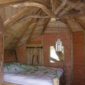 Cabane en bois à Haute-Normandie, avec un lit douillet et des poutres apparentes.