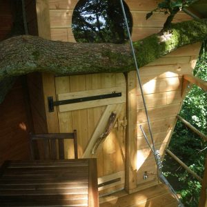 Cabane dans les arbres en Haute-Normandie, avec une porte en bois et une vue sur la nature.