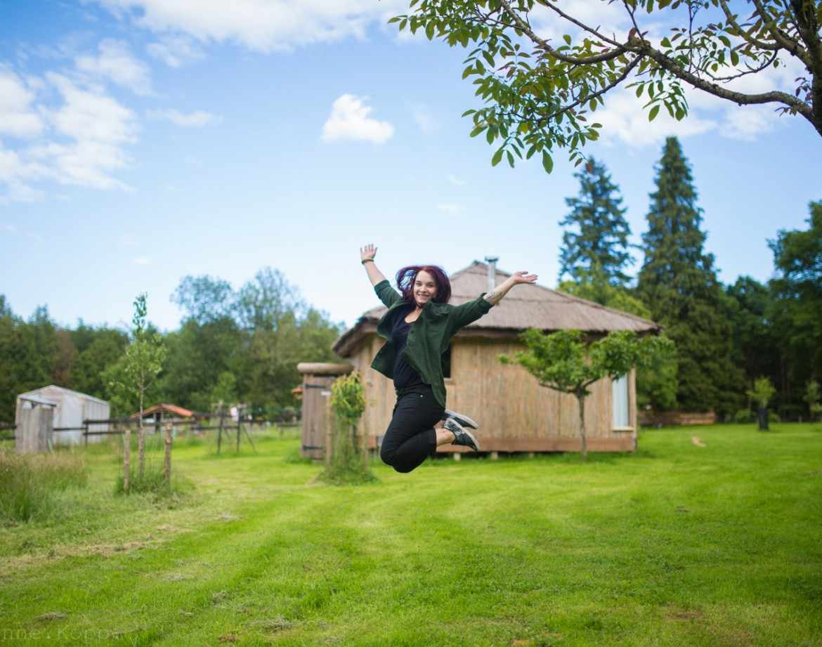 Hébergement insolite en bois dans le Grand-Est, avec une femme sautant joyeusement.