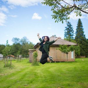 Hébergement insolite en bois dans le Grand-Est, avec une femme sautant joyeusement.