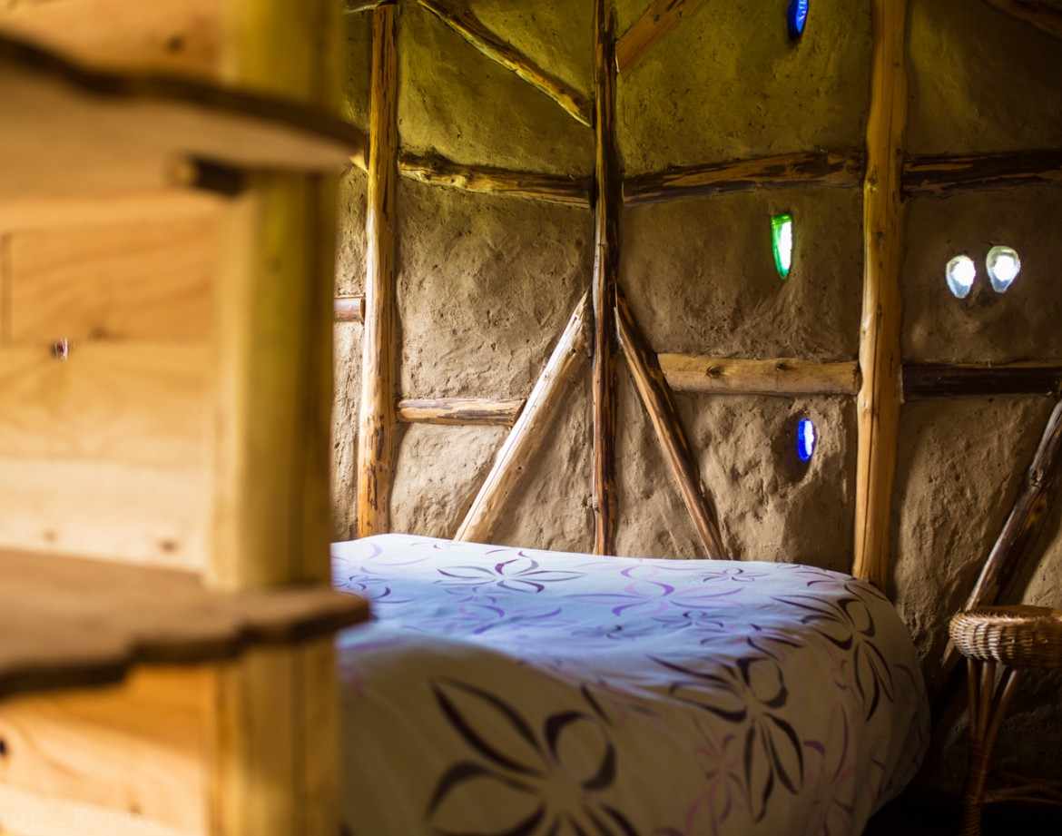 Hébergement insolite en cabane avec murs en terre et fenêtres colorées.