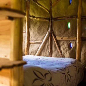 Hébergement insolite en cabane avec murs en terre et fenêtres colorées.
