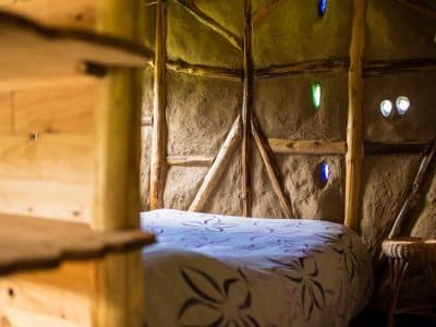 Hébergement insolite en cabane avec murs en terre et fenêtres colorées.