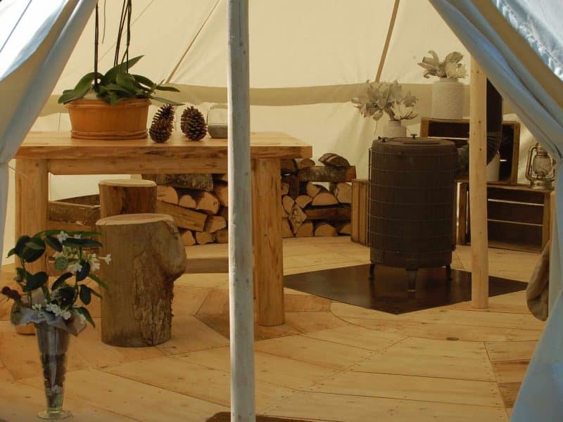 Tente de glamping avec un intérieur en bois chaleureux et une table conviviale.