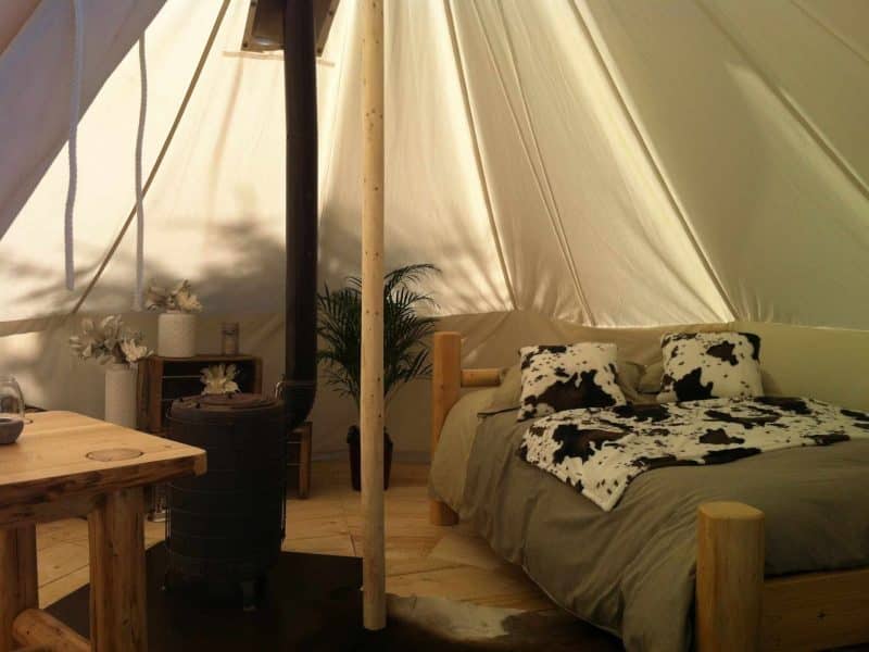 Tente de glamping en Auvergne-Rhône-Alpes, avec lit douillet et décoration naturelle.