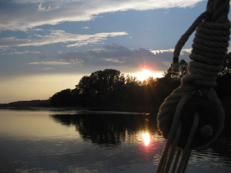 Coucher de soleil sur un hébergement en bord de rivière, ambiance paisible et naturelle.