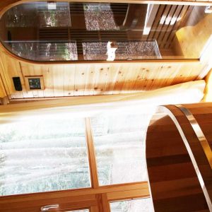 Hébergement insolite en bois avec sauna et baignoire, baigné de lumière naturelle.
