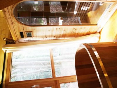 Hébergement insolite en bois avec sauna et baignoire, baigné de lumière naturelle.
