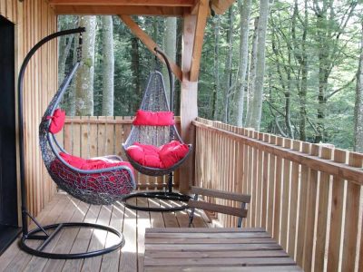 Hébergement insolite en cabane avec balançoires suspendues et vue sur la forêt.