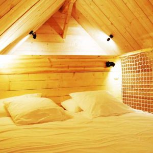 Chalet en bois chaleureux avec lit douillet et lumière tamisée. Parfait pour un séjour romantique.