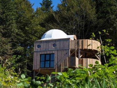 Cabane en bois avec dôme, entourée de verdure en Bourgogne-Franche-Comté.
