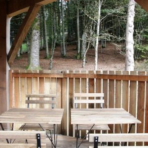 Cabane en bois avec terrasse, entourée de verdure en Bourgogne-Franche-Comté.