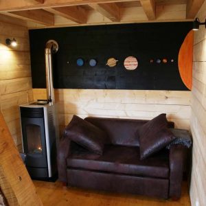 Cabane en bois avec un poêle et un mur décoré des planètes du système solaire.