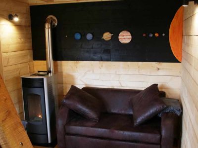 Cabane en bois avec un poêle et un mur décoré des planètes du système solaire.