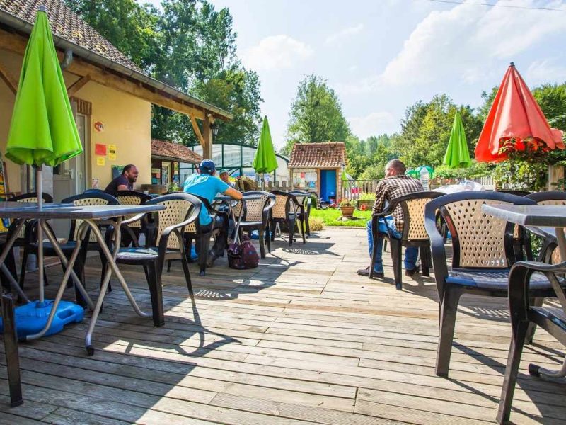 Terrasse dun gîte avec chaises en plastique et parasols colorés, ambiance conviviale.