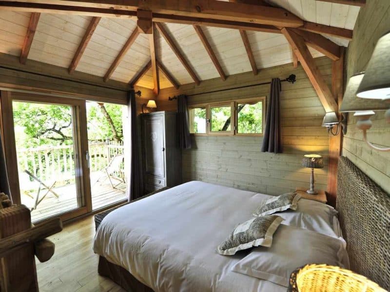 Chalet en bois avec lit douillet et vue sur la nature depuis le balcon.