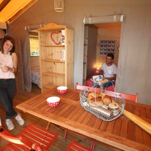 Hébergement insolite en cabane, intérieur chaleureux avec table en bois et petit-déjeuner.