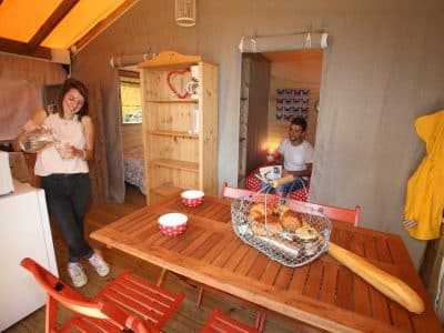 Hébergement insolite en cabane, intérieur chaleureux avec table en bois et petit-déjeuner.