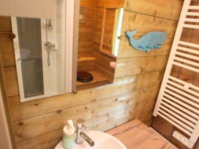 Salle de bain dun hébergement insolite en bois, avec douche et décor marin.