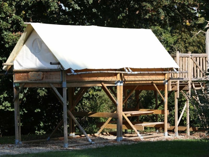 Cabane sur pilotis à Hauts-de-France, avec un toit en toile et une terrasse en bois.