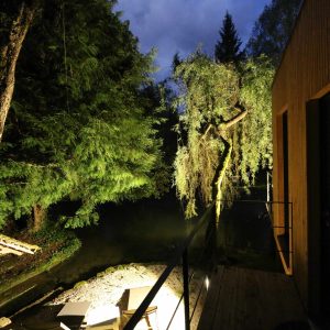 Cabane flottante en Bourgogne, illuminée au bord dun étang entouré darbres.