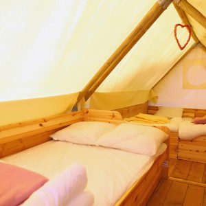 Tente en bois chaleureuse avec lits confortables et décoration accueillante.