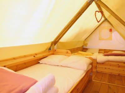 Tente en bois chaleureuse avec lits confortables et décoration accueillante.