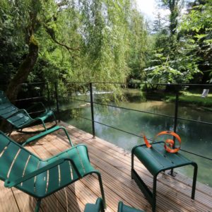Hébergement insolite en Bourgogne : terrasse en bois avec chaises, vue sur la rivière.