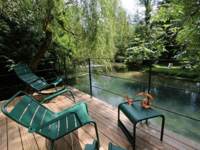 Hébergement insolite en Bourgogne : terrasse en bois avec chaises, vue sur la rivière.