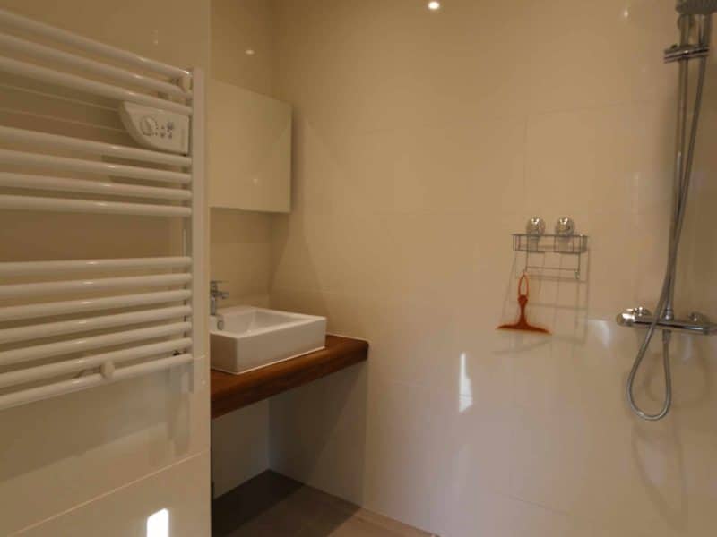 Salle de bain moderne dun hébergement touristique, avec douche et carrelage en galets.