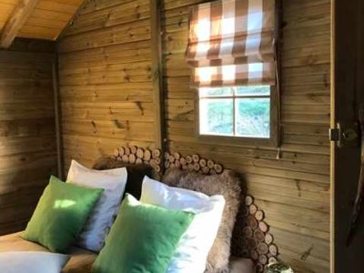 Cabane en bois à Île-de-France, avec un lit douillet et des coussins verts.