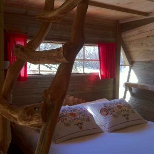 Cabane perchée en Île-de-France avec un lit douillet et des rideaux rouges.