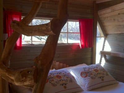 Cabane perchée en Île-de-France avec un lit douillet et des rideaux rouges.