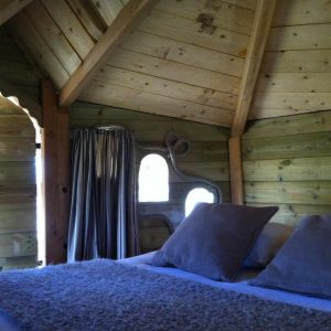 Cabane en bois cosy à Ile-de-France, avec un lit douillet et des murs en bois naturel.