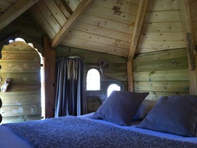 Cabane en bois cosy à Ile-de-France, avec un lit douillet et des murs en bois naturel.