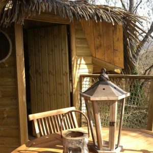 Cabane perchée en Île-de-France avec terrasse en bois et lanternes décoratives.