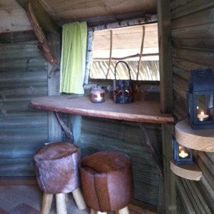Cabane insolite en Île-de-France avec tabourets en peau et ambiance chaleureuse.