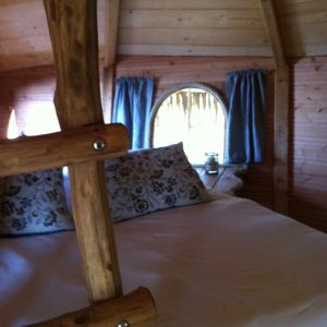 Cabane en bois à lIle-de-France, avec fenêtre ronde et lit douillet.