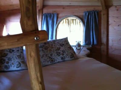 Cabane en bois à lIle-de-France, avec fenêtre ronde et lit douillet.