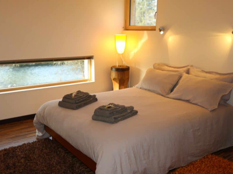 Chambre dhôtes moderne avec vue sur la rivière et linge de lit soigné.