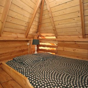 Cabane en bois avec lit douillet et décorations en forme de cœur.
