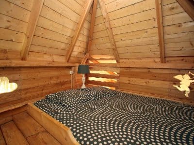 Cabane en bois avec lit douillet et décorations en forme de cœur.