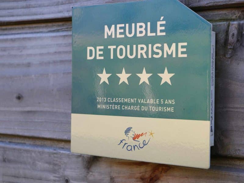 Meublé de tourisme 4 étoiles, plaque informative sur un mur en bois.