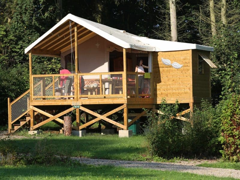 Cabane en bois sur pilotis, entourée de verdure, idéale pour un séjour insolite.