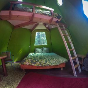 Cabane insolite en forme de tipi avec lit mezzanine et décoration colorée.