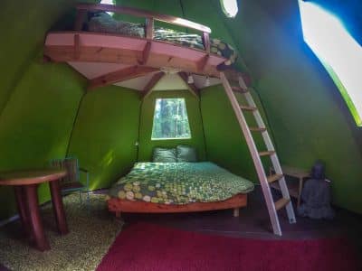 Cabane insolite en forme de tipi avec lit mezzanine et décoration colorée.
