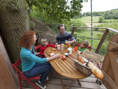 Cabane dans les arbres en Hauts-de-France, famille profitant dun petit déjeuner en plein air.