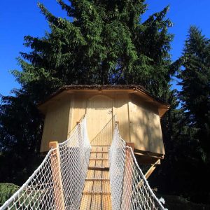 Cabane dans les arbres en Auvergne-Rhône-Alpes, accessible par un pont suspendu.